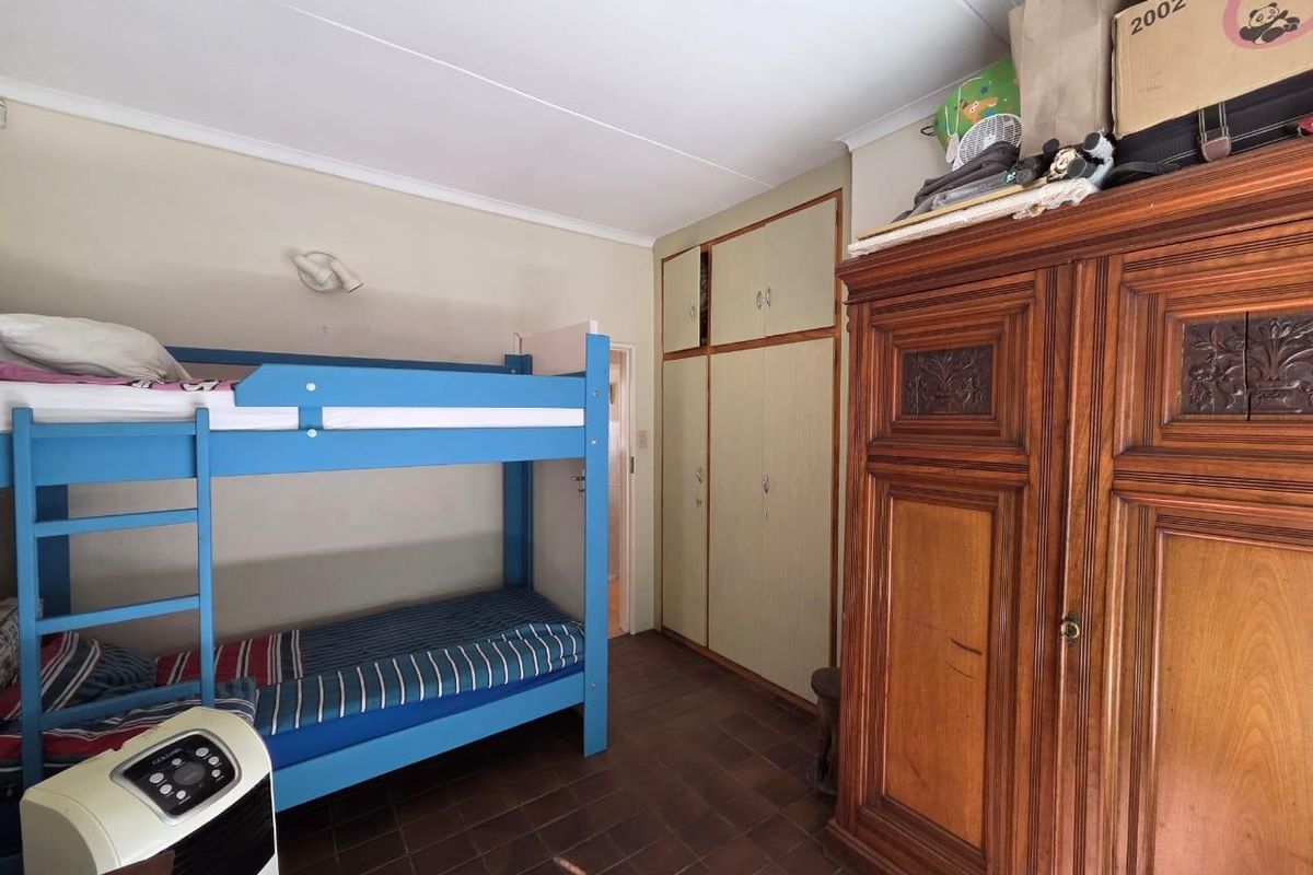 A bedroom featuring built-in cupboards and tiled flooring, offering a functional space that could benefit from cosmetic updates to modernize the interior finishes.