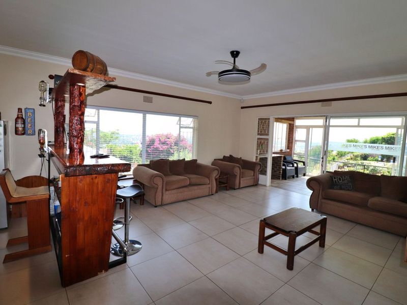 Spacious living room featuring tiled flooring, a ceiling fan, and large sliding glass doors that provide natural light and access to the patio area.