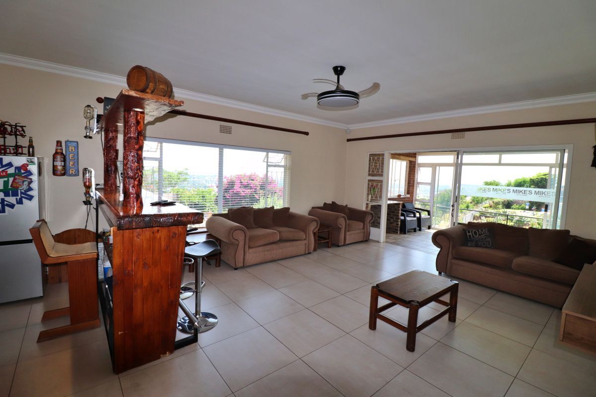 Spacious living room featuring tiled flooring, a ceiling fan, and large sliding glass doors that provide natural light and access to the patio area.