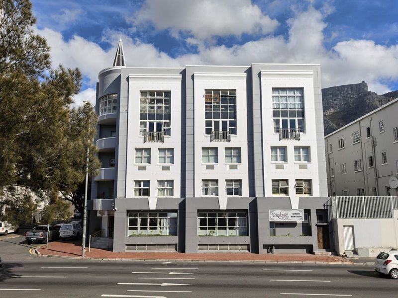 Front elevation of a multi-story apartment building featuring a distinctive architectural spire, large windows, and balconies overlooking the street.