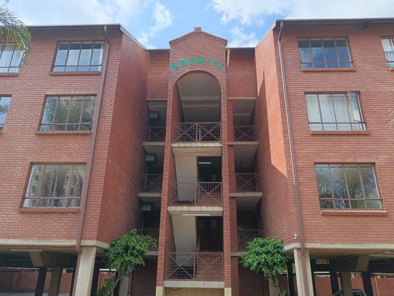 Front elevation of a multi-story apartment building featuring face brick construction, open stairwell access, and ground-level covered parking.