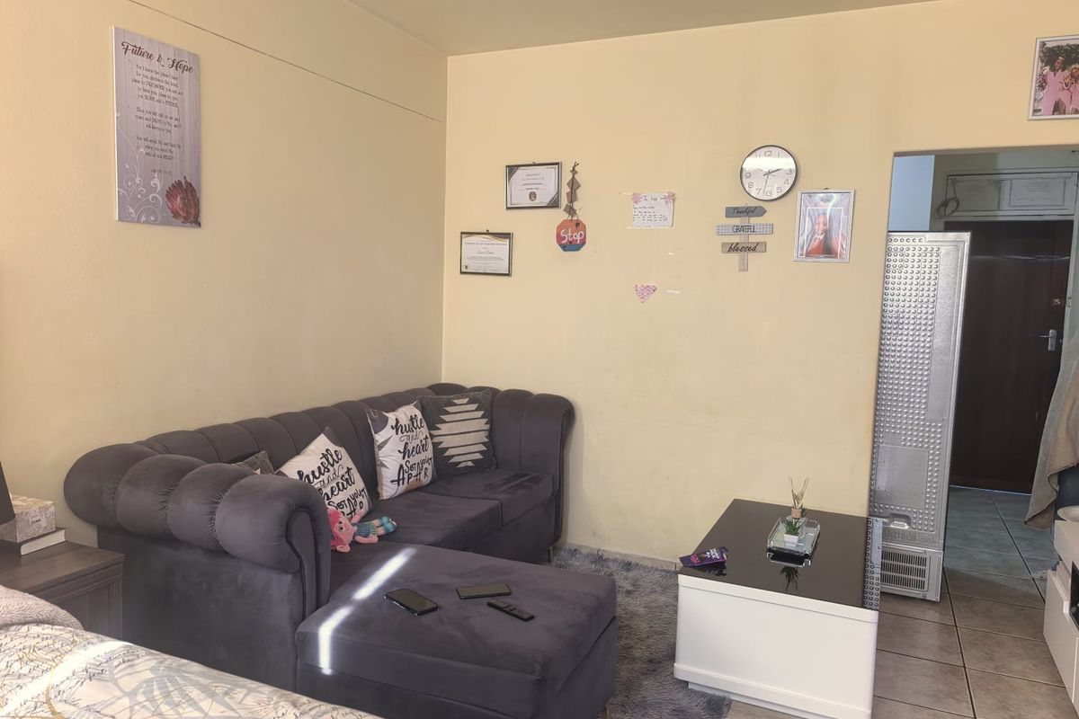 A living room area featuring tiled flooring and a doorway leading to an adjacent space.