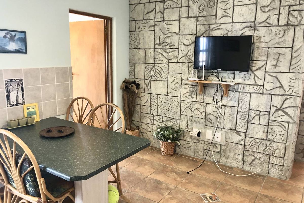 A living area featuring a textured stone-cladding feature wall, tiled flooring, and a built-in dining counter.
