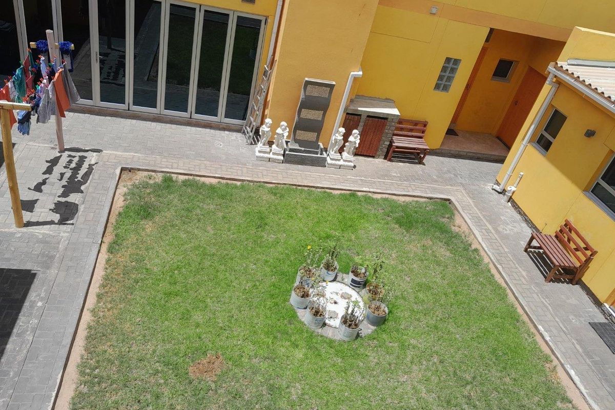 An elevated view of a central courtyard featuring a grass lawn, paved walkways, and access to the surrounding building structure.