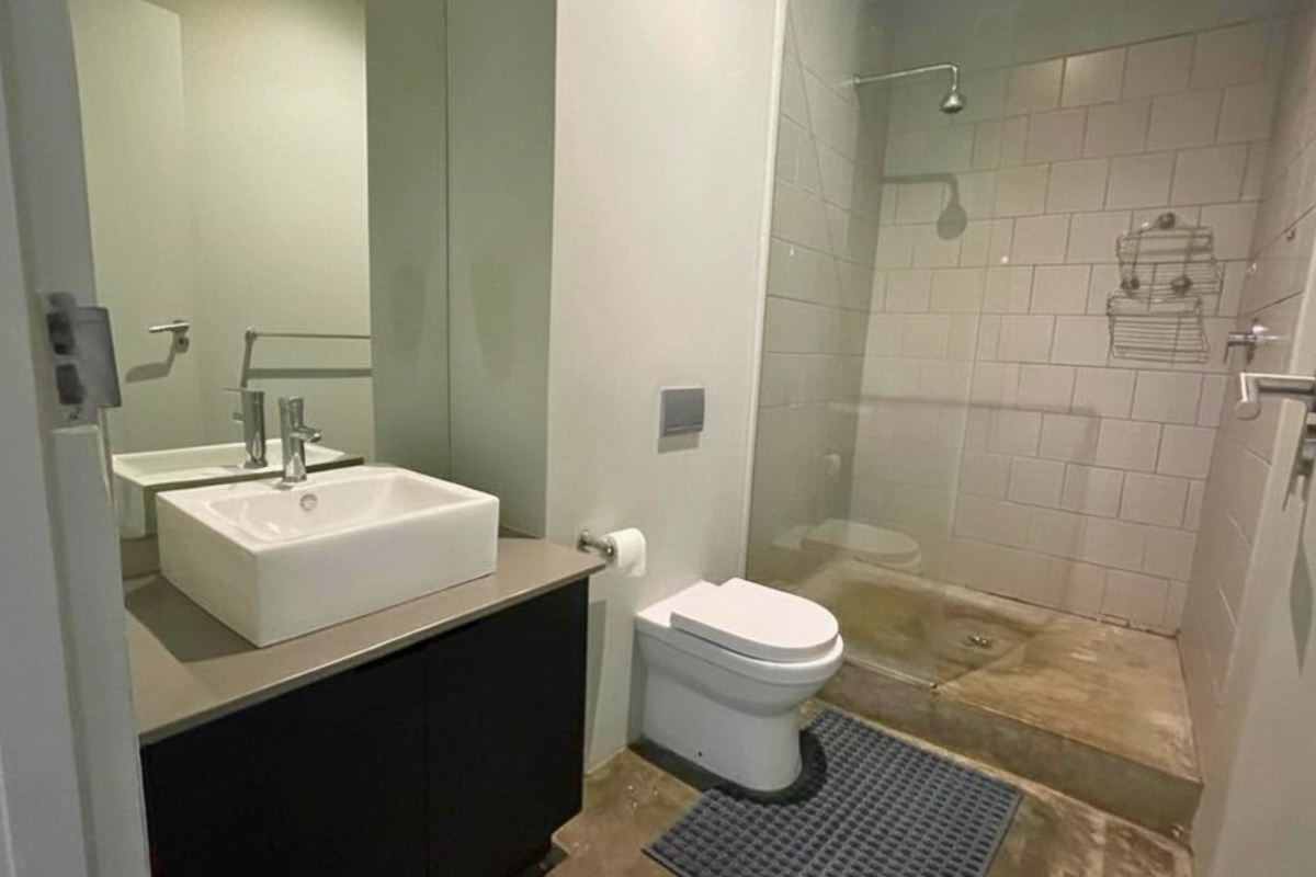 Modern bathroom featuring a vessel sink vanity, wall-mounted toilet, and a walk-in shower with subway tile surround and glass partition.