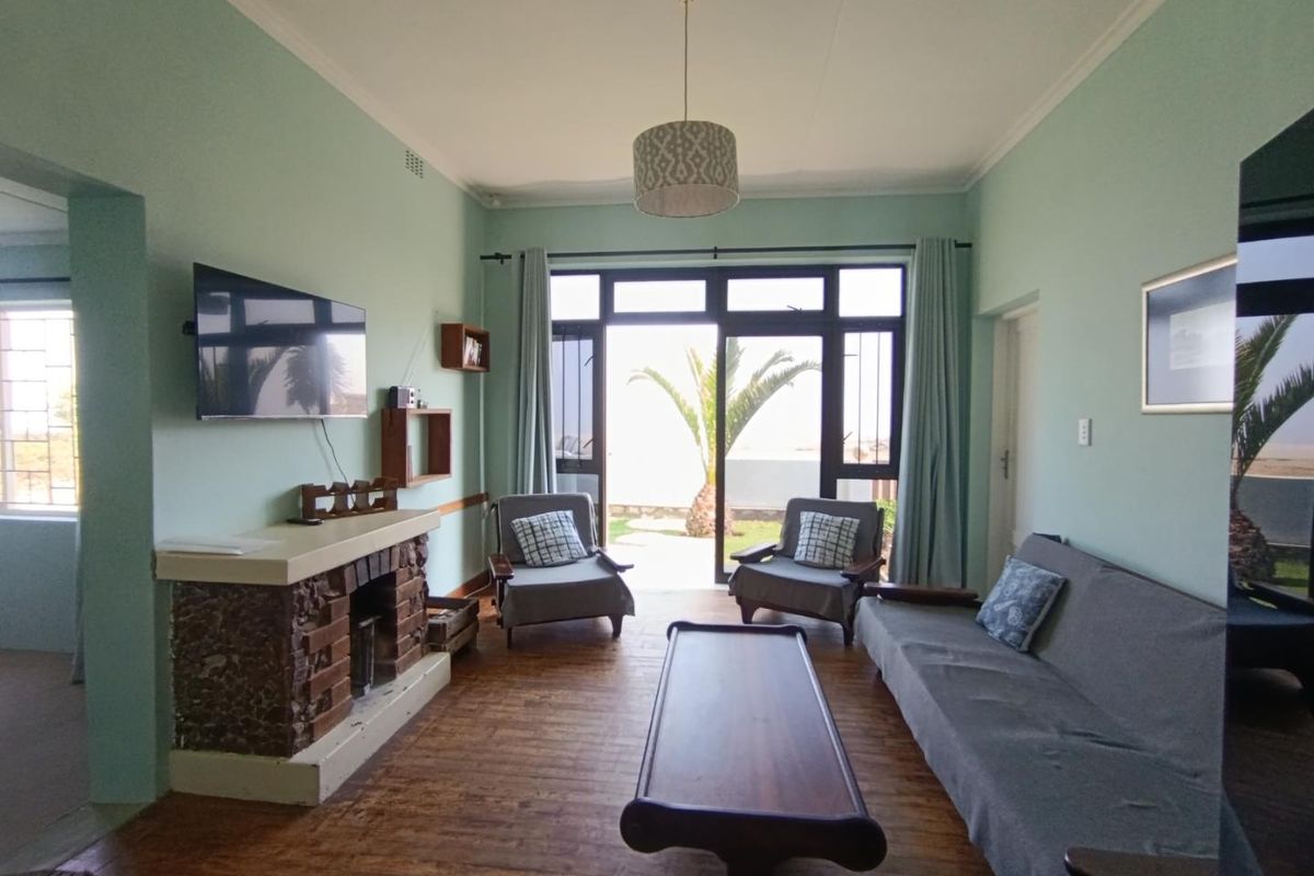 A living room featuring a brick fireplace, wooden flooring, and large glass sliding doors providing direct access to the garden.