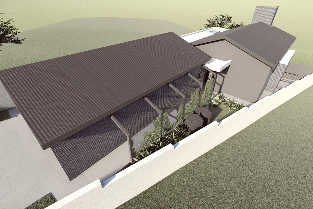 An aerial perspective of a modern residential property featuring a corrugated metal roof, brick exterior, and a secure perimeter wall.