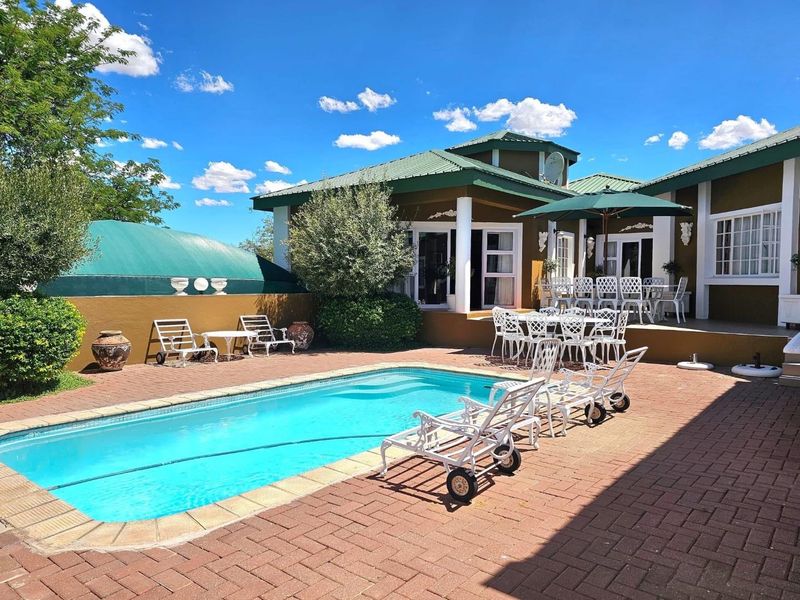 Outdoor pool area featuring a swimming pool, brick paved surround, and a covered patio area attached to the main house structure.