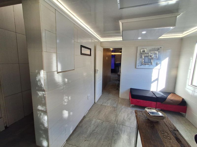 A modern living area featuring tiled wall finishes, recessed ceiling lighting, and large format floor tiles, creating a clean and contemporary aesthetic.