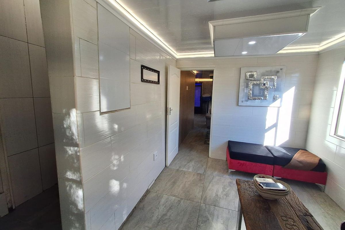 A modern living area featuring tiled wall finishes, recessed ceiling lighting, and large format floor tiles, creating a clean and contemporary aesthetic.