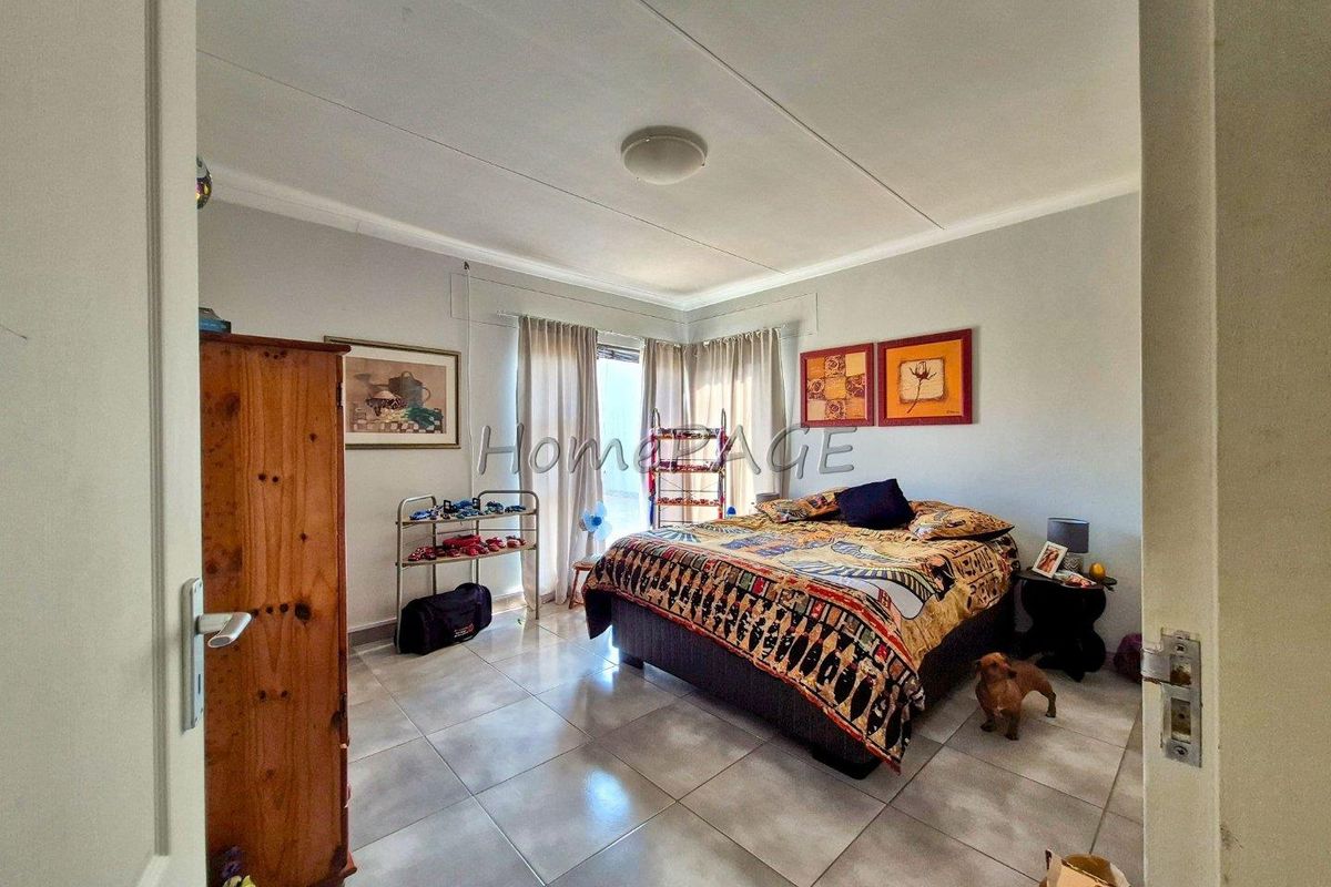 A bedroom featuring tiled flooring, neutral wall finishes, and natural light provided by a window with curtain rails.