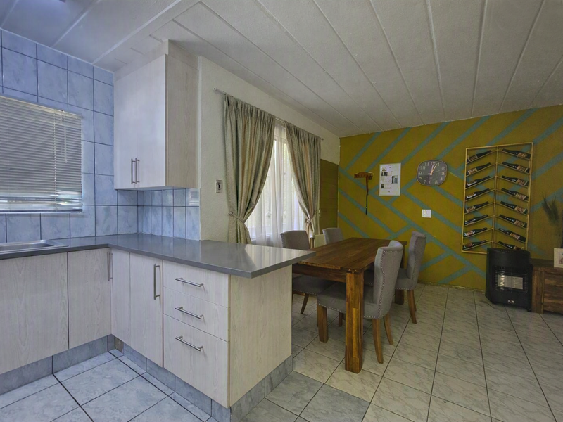 Open plan kitchen and dining area featuring light wood-look cabinetry, tiled splashbacks, and neutral floor tiles, offering a functional layout for daily living.