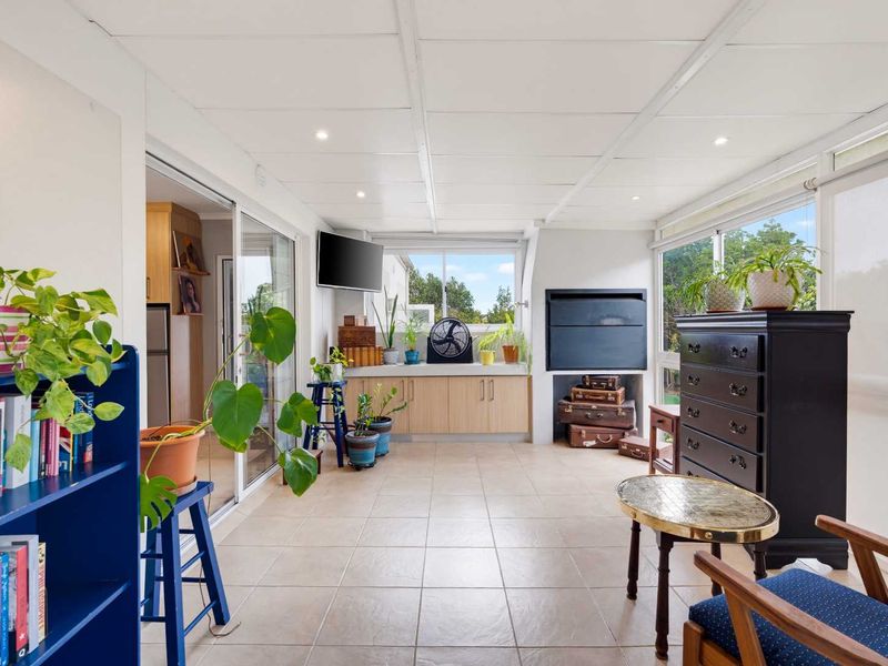 Enclosed patio area featuring tiled flooring, built-in cabinetry, and a fireplace, providing a versatile space with direct access to the kitchen.