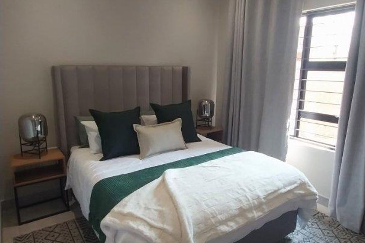 A well-maintained bedroom featuring neutral wall tones, tiled flooring, recessed downlighting, and a window fitted with security bars.