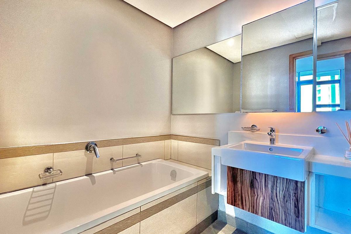 Modern bathroom featuring a built-in bathtub with wall-mounted fixtures, a floating vanity cabinet with integrated sink, and a large wall mirror.
