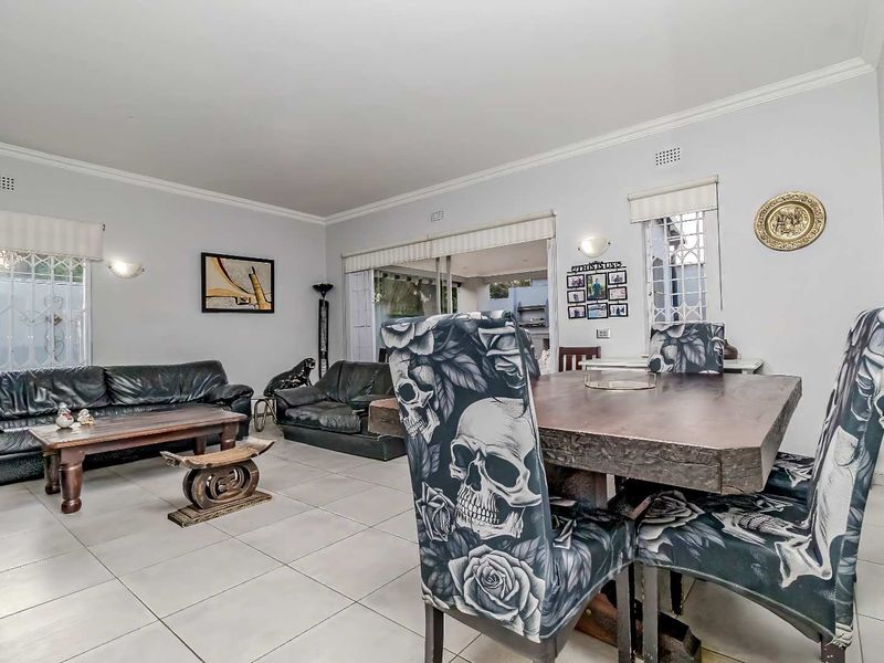 Spacious open-plan living and dining area featuring neutral tiled flooring, crown molding, and large sliding doors providing access to the outdoor space.