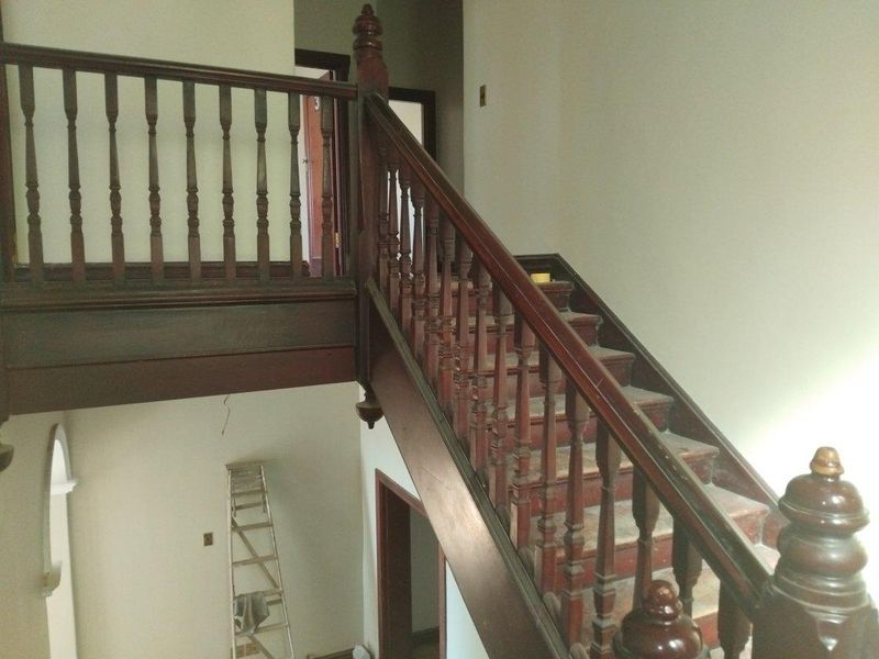 A traditional timber staircase featuring a classic balustrade and handrail, currently showing signs of wear and requiring cosmetic refurbishment.