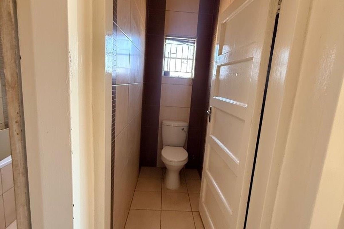 A compact bathroom featuring tiled flooring, wall tiles, and a standard toilet fixture.