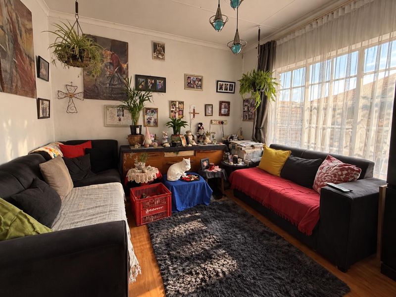 A cozy living room featuring large windows that provide ample natural light and laminate flooring throughout.