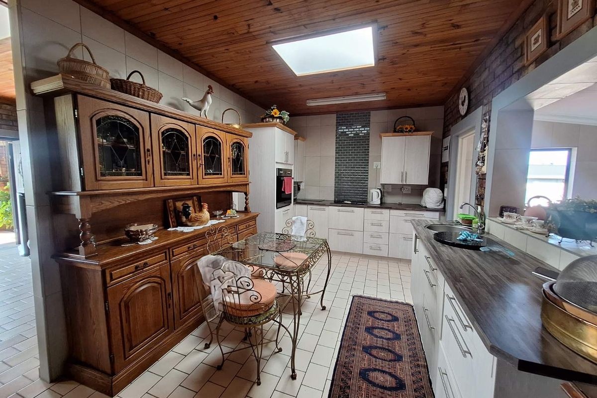 A functional kitchen featuring white cabinetry, dark countertops, a built-in oven, and a distinctive timber-paneled ceiling with a skylight.