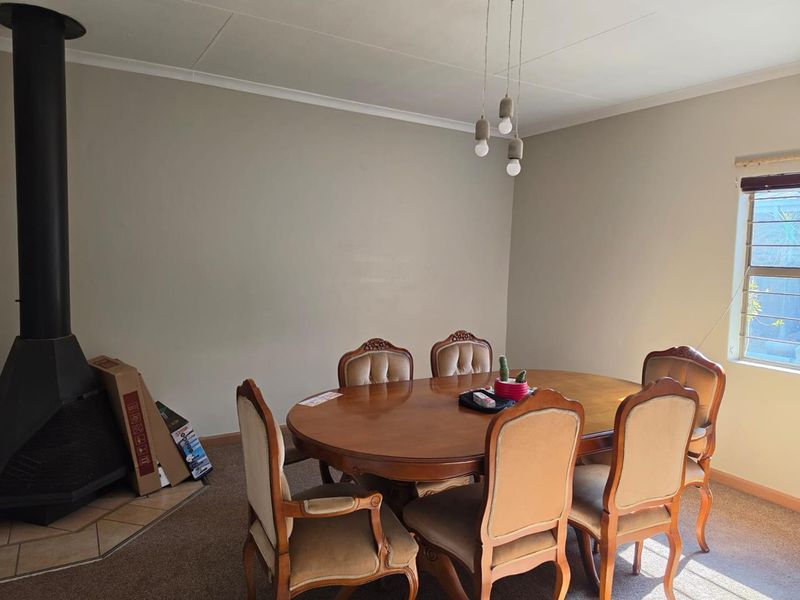 Dining room featuring a freestanding fireplace with a tiled hearth and pendant lighting, offering a functional space for family meals.