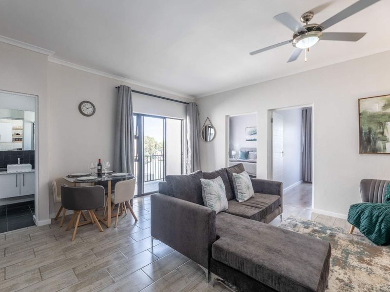 An open-plan living and dining area featuring tiled floors, a ceiling fan, and direct access to a balcony through sliding glass doors.