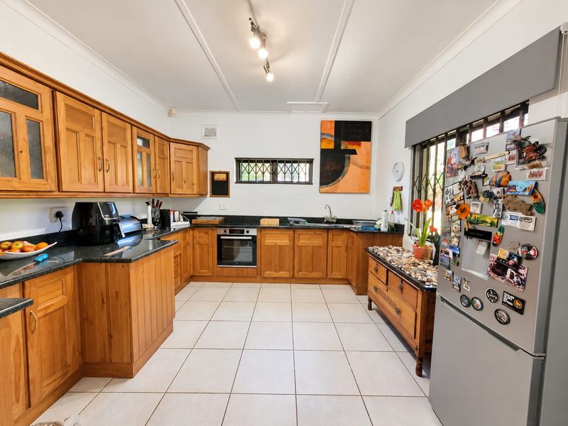 A functional kitchen featuring warm wooden cabinetry, granite countertops, built-in oven, and tiled flooring, offering a classic and practical layout.
