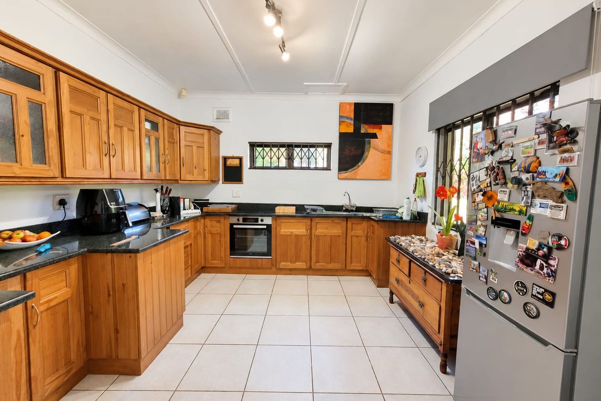 A functional kitchen featuring warm wooden cabinetry, granite countertops, built-in oven, and tiled flooring, offering a classic and practical layout.