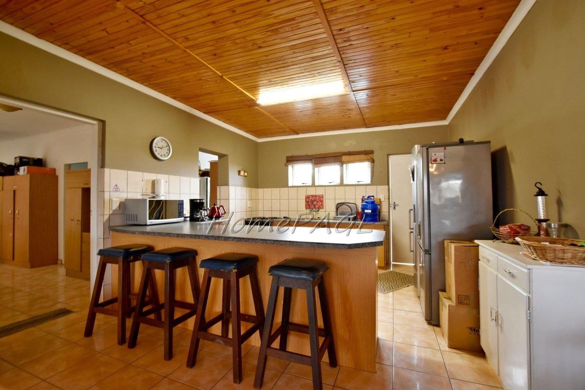 A functional kitchen featuring a breakfast bar, tiled splashbacks, and a distinctive timber-paneled ceiling, providing a practical layout for daily meal preparation.
