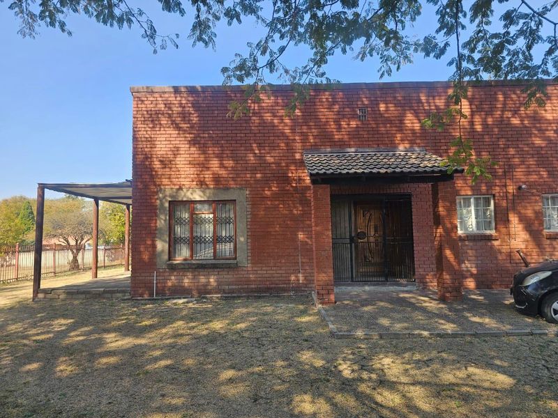 Front elevation of a face brick house featuring a covered entrance porch, security gates, and an attached side patio area.