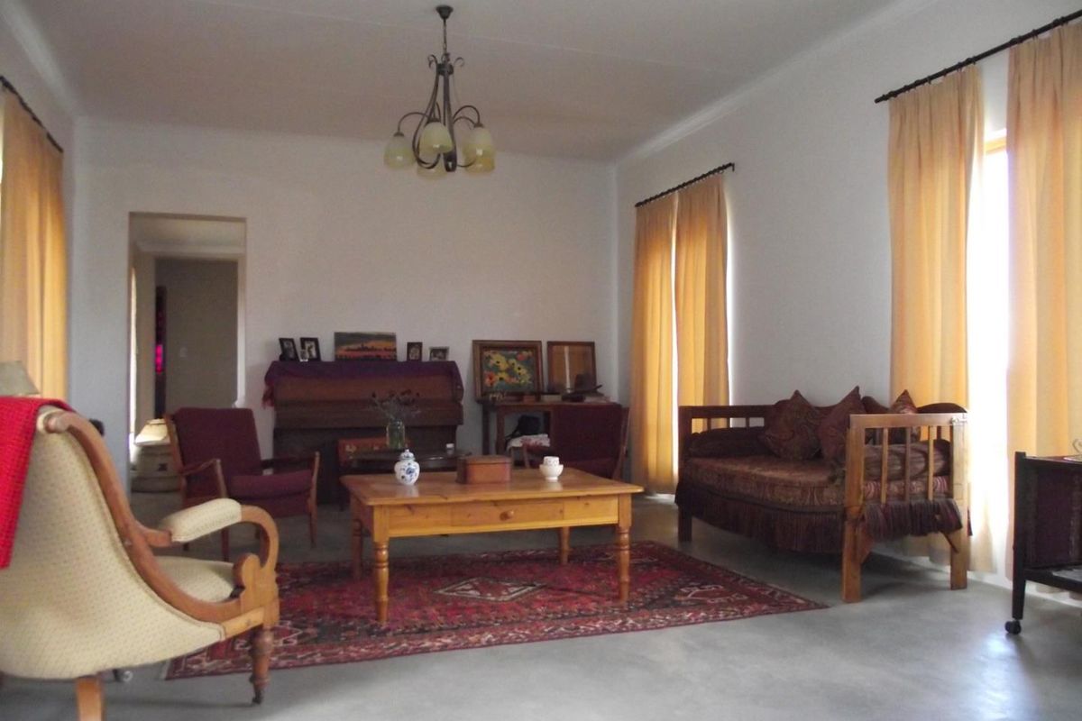 Spacious living room featuring polished concrete flooring, neutral walls, and large windows with natural light, providing a versatile area for relaxation.