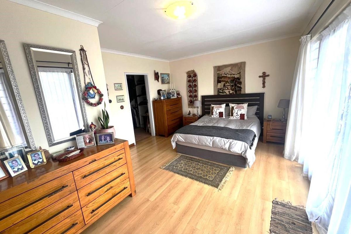 Spacious bedroom featuring light wood-look laminate flooring, a built-in closet, and large windows allowing for ample natural light.