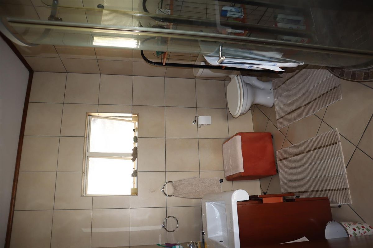 A functional bathroom featuring tiled walls and floors, a shower enclosure, a toilet, and a vanity basin.