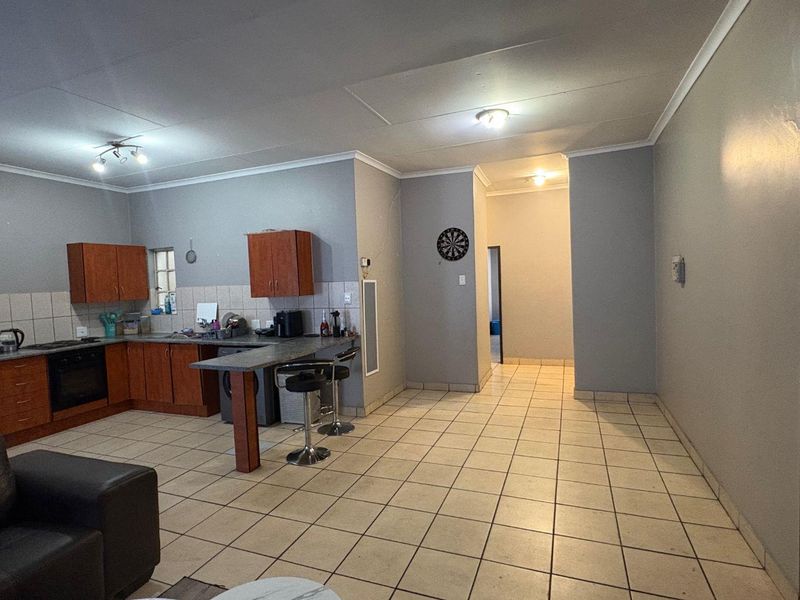 Open plan living area featuring a functional kitchen with built-in cabinetry, oven, and tiled flooring throughout the space.