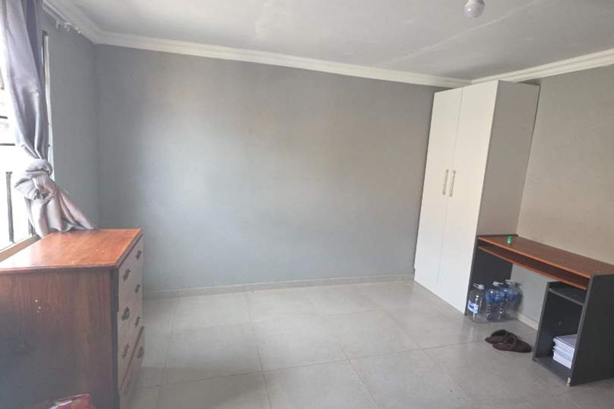 A bedroom featuring tiled flooring, coving, and a built-in wardrobe, with visible ceiling cracks requiring attention.