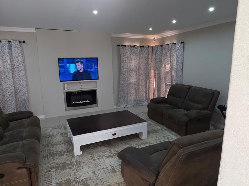 A comfortable living room featuring a built-in electric fireplace, recessed downlighting, and neutral tiled flooring.