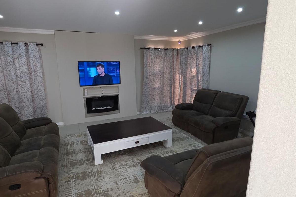 A comfortable living room featuring a built-in electric fireplace, recessed downlighting, and neutral tiled flooring.