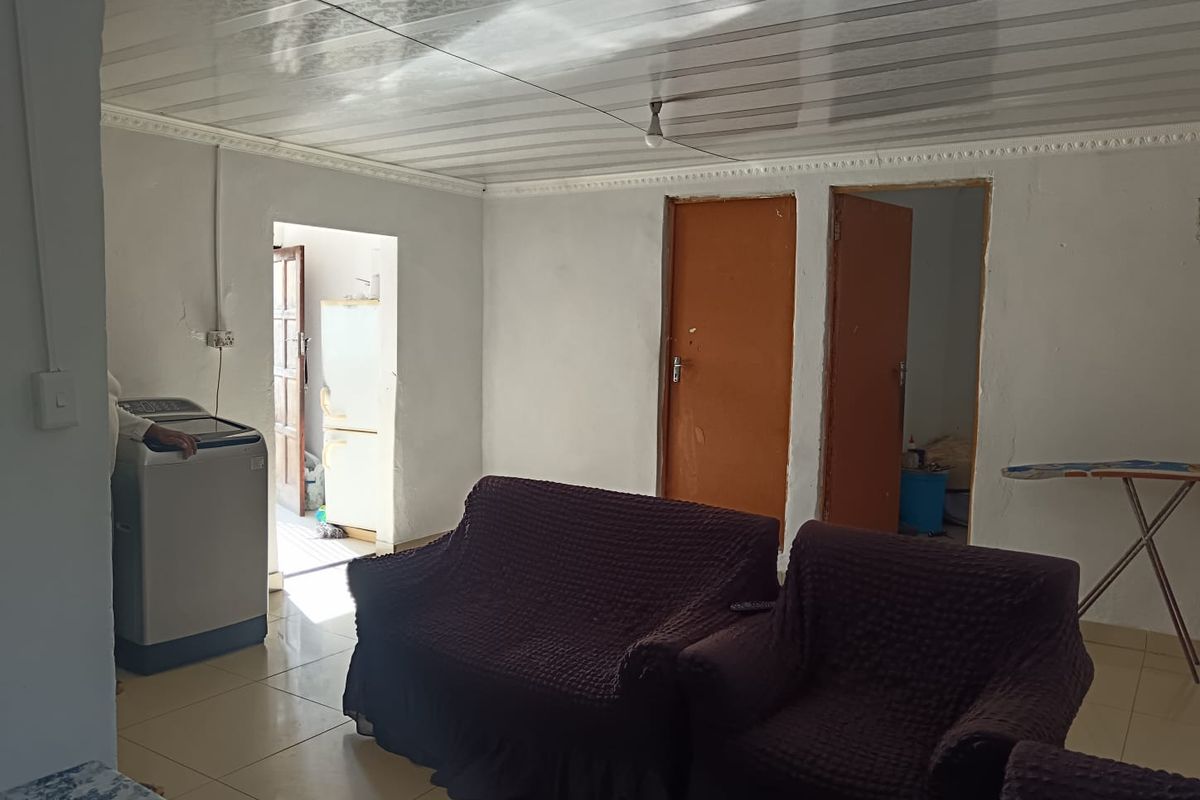 A living area featuring tiled floors and plastic ceiling panels, showing signs of wear and requiring cosmetic updates to improve the overall finish.