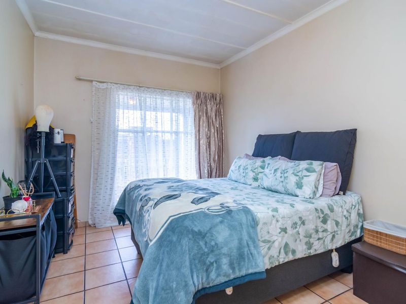 A bedroom featuring tiled flooring and a window with a curtain rail.