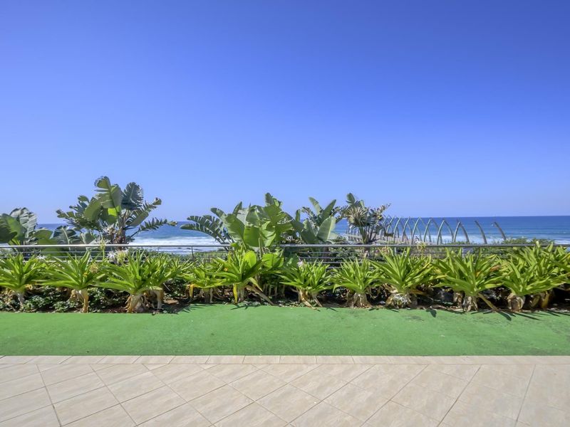 A spacious balcony featuring tiled flooring, artificial turf, and a stainless steel balustrade, offering an unobstructed view of the ocean.