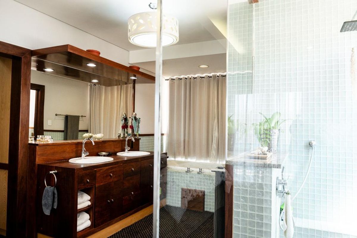 Spacious bathroom featuring a dark wood double vanity with dual sinks, a large mirror, a glass-enclosed shower with mosaic tiling, and a built-in bathtub.