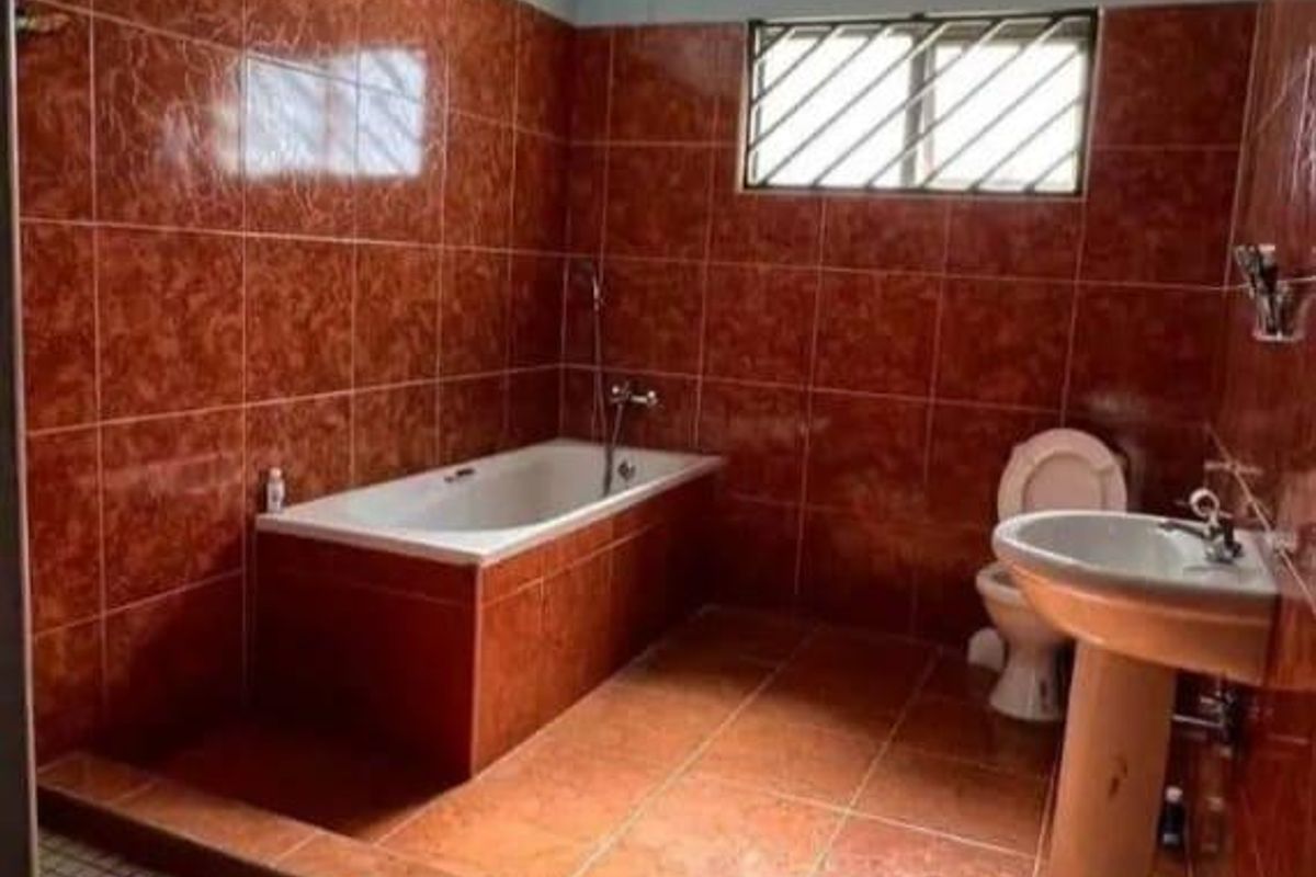 A functional bathroom featuring a built-in bathtub, a pedestal sink, and a separate shower area with tiled finishes throughout.