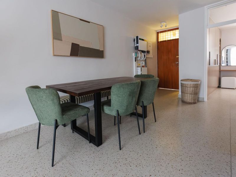 A bright living area featuring modern terrazzo flooring, a timber entrance door, and a wall-mounted inverter system.