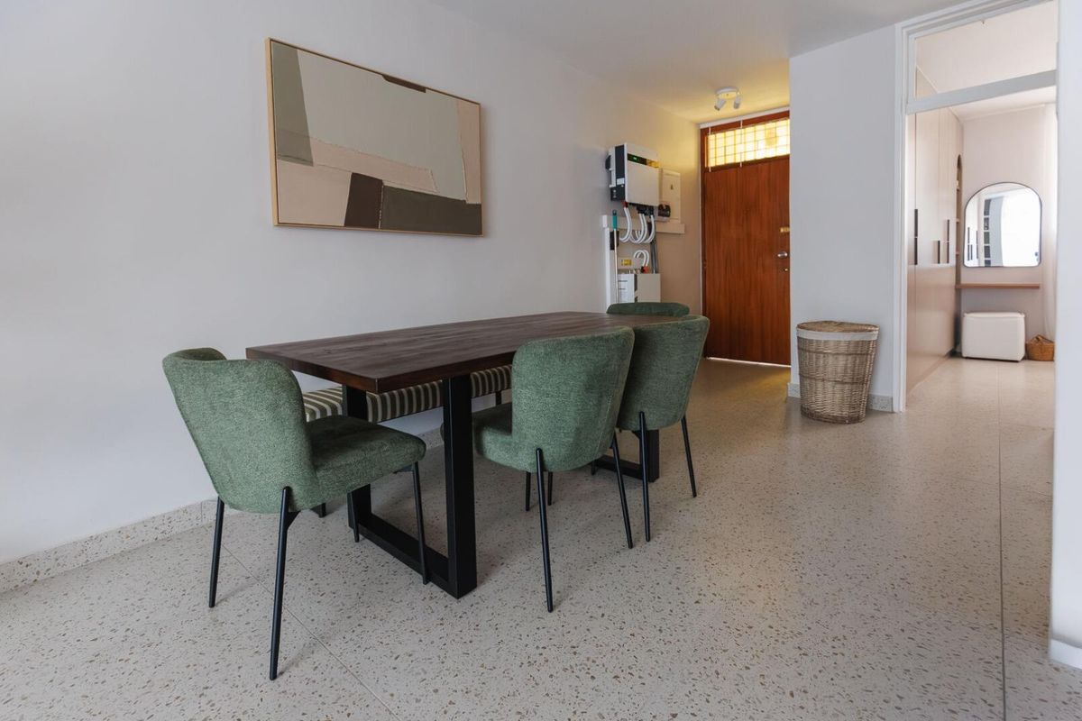 A bright living area featuring modern terrazzo flooring, a timber entrance door, and a wall-mounted inverter system.