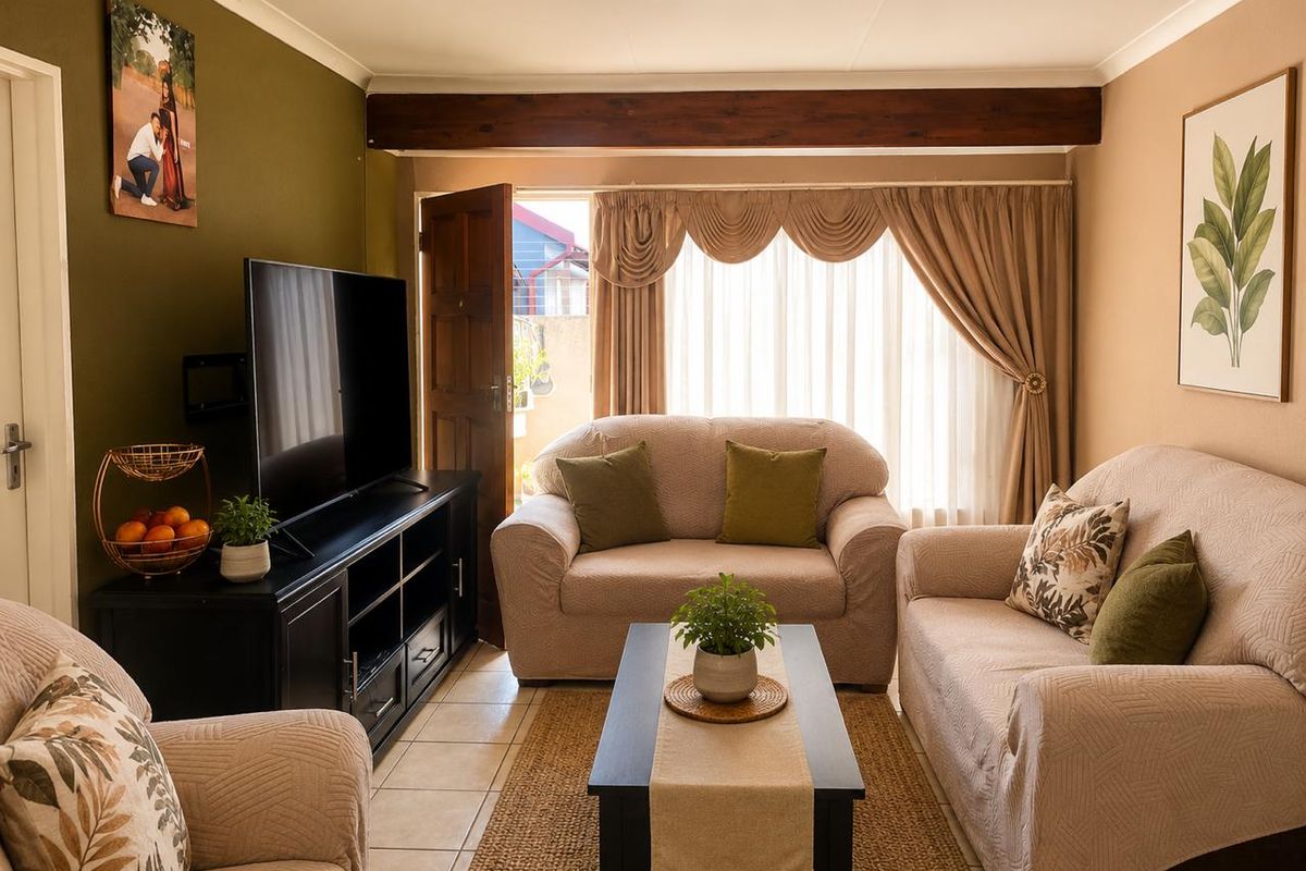 A cozy living room featuring tiled flooring, an exposed timber ceiling beam, and direct access to an outdoor area through a sliding door.