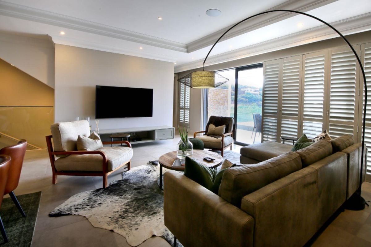 Spacious living room featuring recessed ceiling lighting, crown molding, large sliding glass doors with plantation shutters, and neutral tiled flooring.