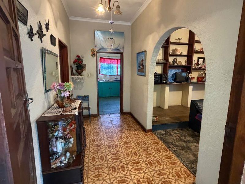 A traditional entrance hallway featuring an arched opening leading to an adjacent living space, with classic tiled flooring and built-in shelving.