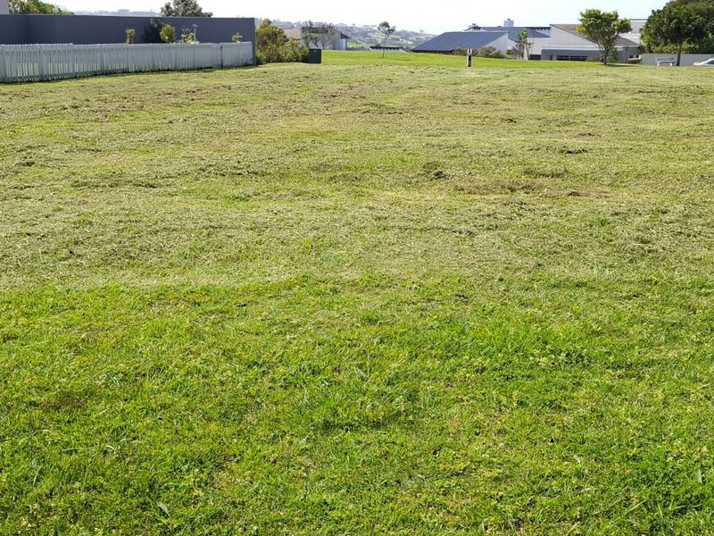 A clear, level residential vacant land plot featuring a well-maintained grassed lawn and perimeter fencing in a developed neighborhood.