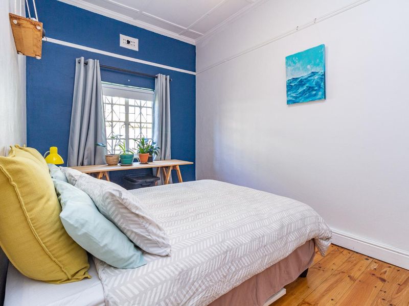 A well-maintained bedroom featuring polished timber flooring, a decorative coved ceiling, and a window fitted with security bars.