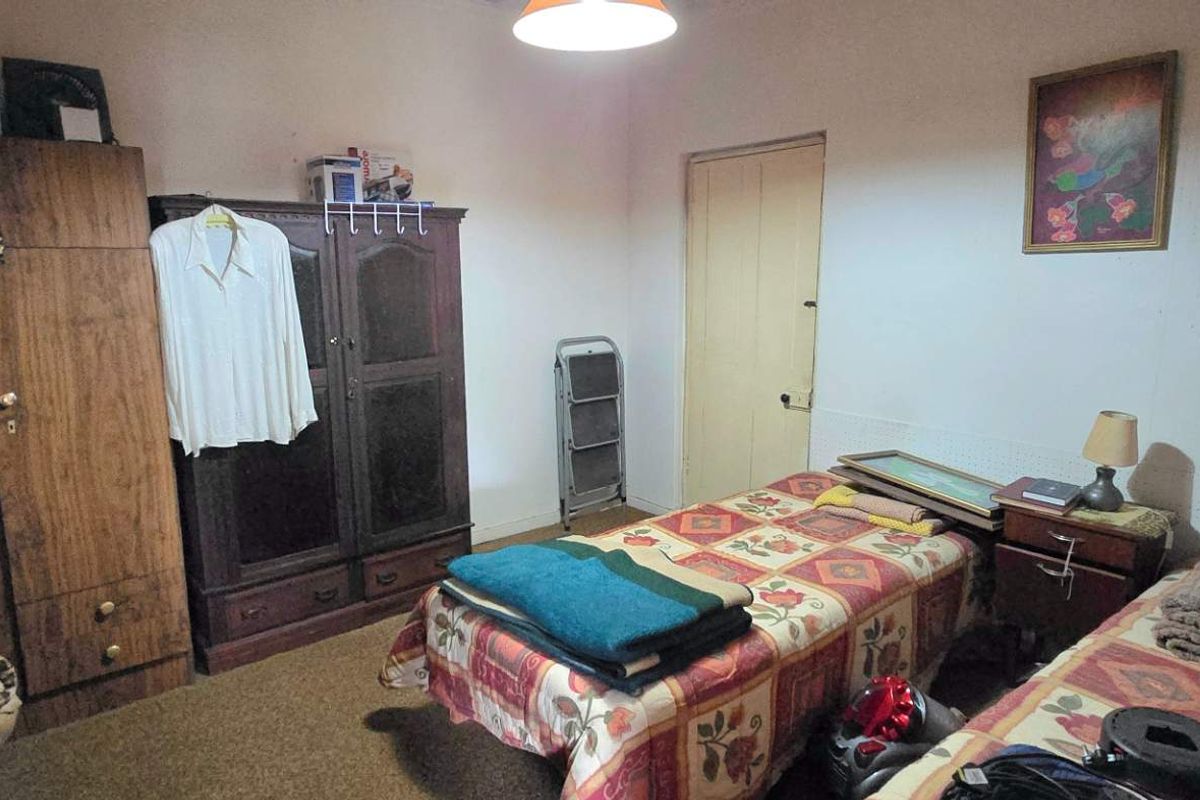A bedroom featuring a standard layout with a pendant light fixture and internal door access, requiring cosmetic updates to improve the overall finish.